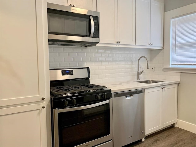 kitchen with light stone countertops, white cabinets, dark wood-type flooring, stainless steel appliances, and sink