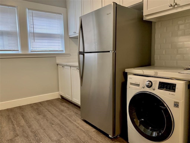 clothes washing area with light hardwood / wood-style floors and washer / dryer