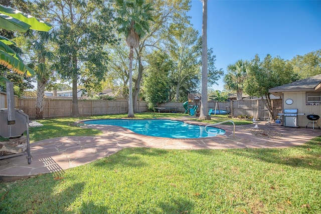 view of pool with a lawn, grilling area, a patio, and a playground