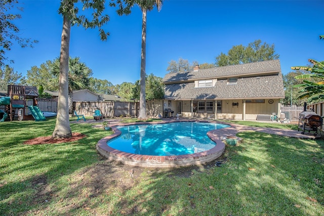 view of swimming pool with a playground and a lawn