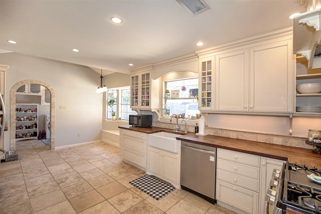 kitchen with pendant lighting, lofted ceiling, stainless steel appliances, sink, and butcher block countertops