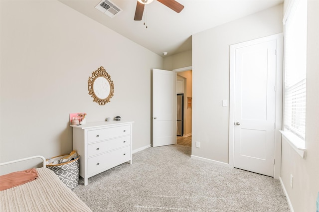 bedroom with ceiling fan, light carpet, and stainless steel fridge