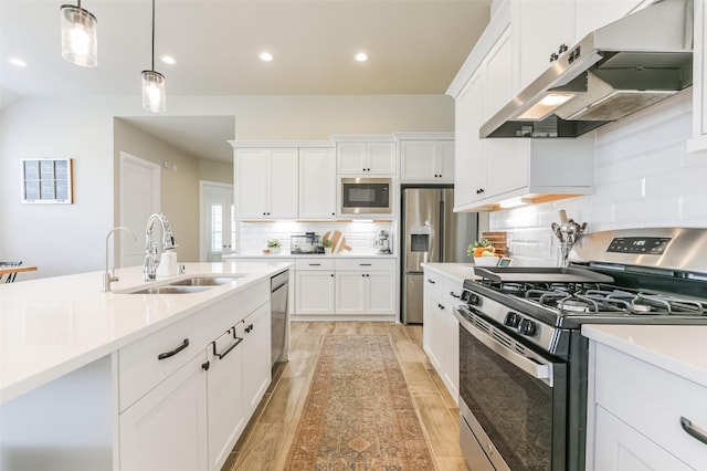 kitchen featuring appliances with stainless steel finishes, decorative light fixtures, white cabinetry, tasteful backsplash, and sink