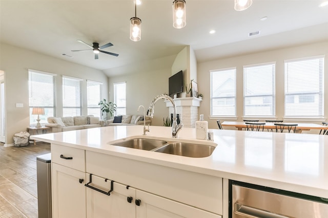 kitchen with light hardwood / wood-style floors, white cabinets, hanging light fixtures, and sink