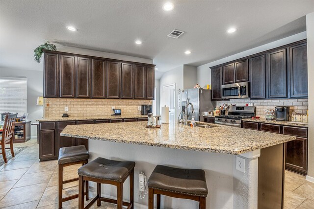 kitchen with stainless steel appliances, a breakfast bar area, and an island with sink