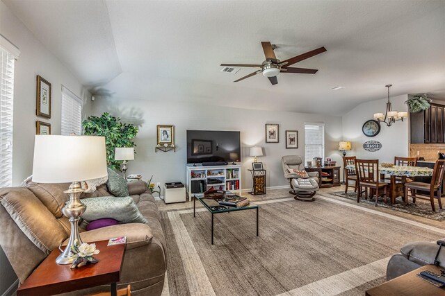 living room with a healthy amount of sunlight, carpet flooring, lofted ceiling, and ceiling fan with notable chandelier