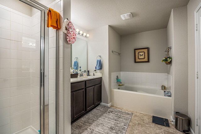 bathroom featuring a textured ceiling, independent shower and bath, and vanity