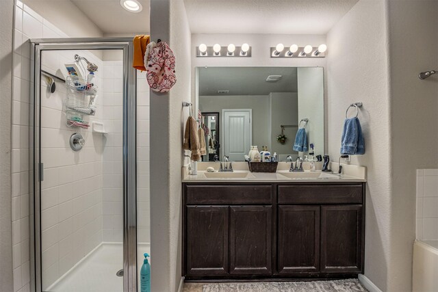 bathroom featuring a shower with shower door and vanity