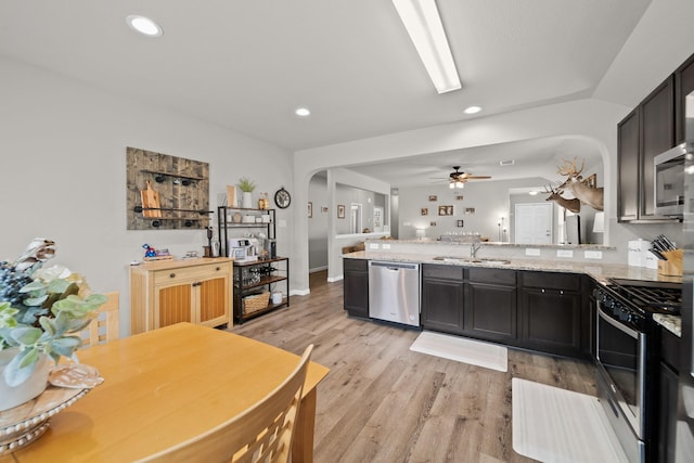 kitchen with kitchen peninsula, light stone countertops, sink, and stainless steel appliances