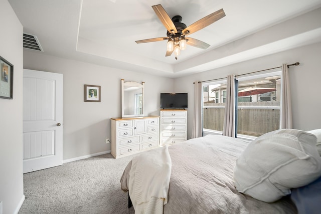 carpeted bedroom with ceiling fan and a raised ceiling