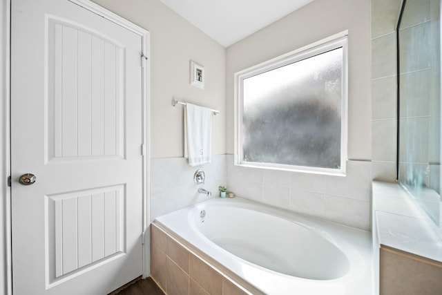 bathroom featuring a wealth of natural light and tiled tub