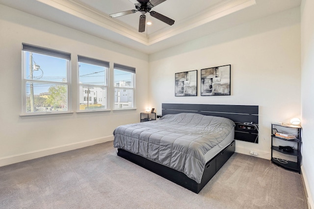 carpeted bedroom with ceiling fan, ornamental molding, and a raised ceiling