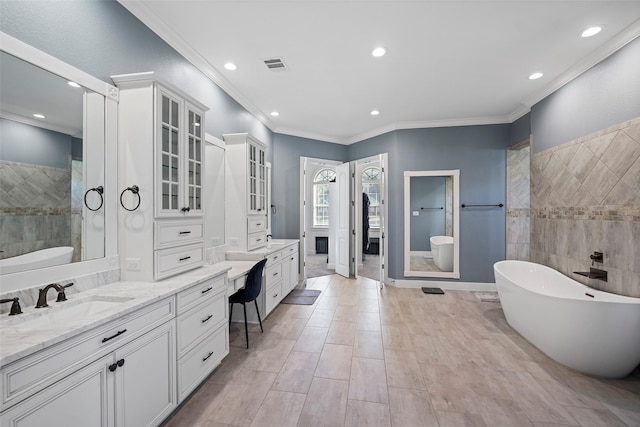 full bathroom featuring a soaking tub, vanity, visible vents, and crown molding