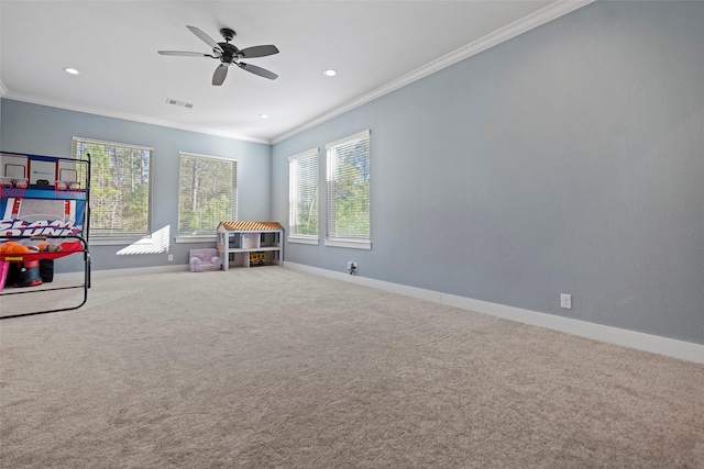 recreation room featuring carpet floors, crown molding, a wealth of natural light, visible vents, and baseboards