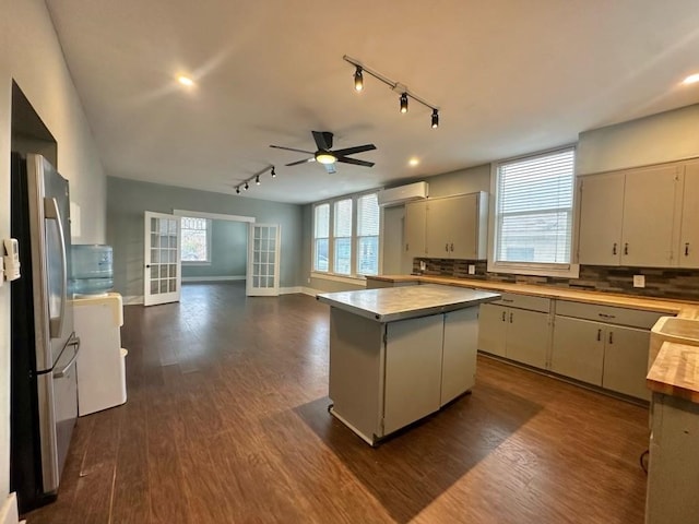 kitchen featuring dark hardwood / wood-style flooring, stainless steel fridge, a center island, and backsplash