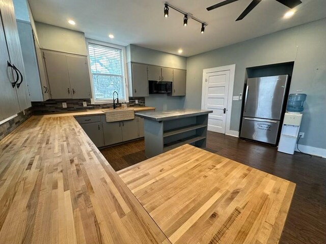 kitchen featuring gray cabinetry, dark hardwood / wood-style flooring, stainless steel fridge, and a kitchen island