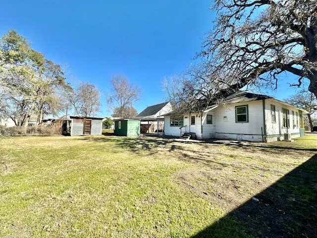 rear view of property featuring a storage unit and a yard