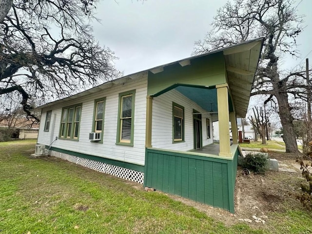 view of home's exterior featuring cooling unit, a porch, and a lawn