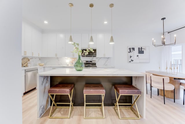 kitchen featuring a breakfast bar, pendant lighting, white cabinetry, backsplash, and stainless steel appliances