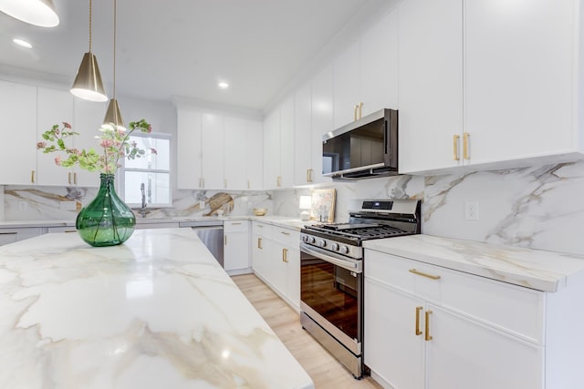 kitchen featuring white cabinetry, light stone counters, hanging light fixtures, stainless steel appliances, and backsplash