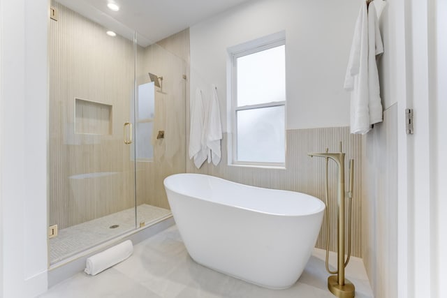 bathroom with tile patterned flooring, shower with separate bathtub, and a healthy amount of sunlight