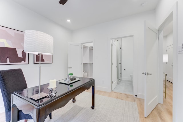 home office with ceiling fan and light hardwood / wood-style flooring