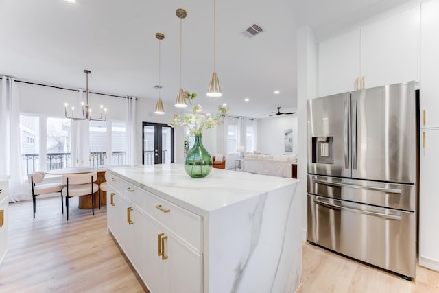 kitchen with a kitchen island, decorative light fixtures, white cabinetry, light stone counters, and stainless steel refrigerator with ice dispenser