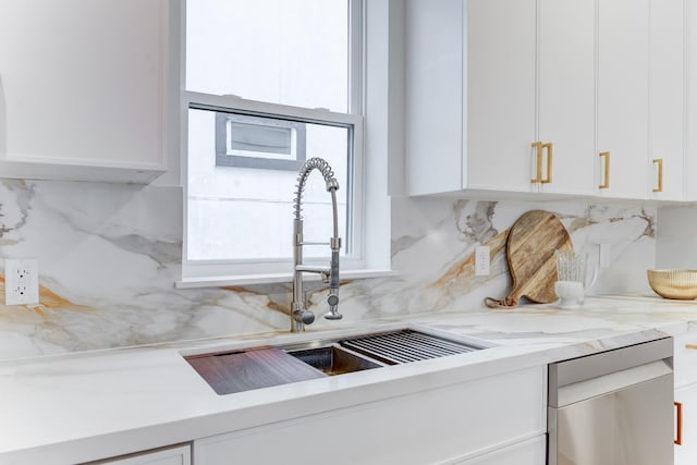 kitchen featuring white cabinets, light stone countertops, sink, and backsplash