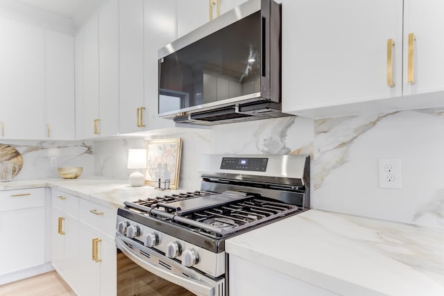 kitchen with decorative backsplash, light stone countertops, white cabinets, and appliances with stainless steel finishes