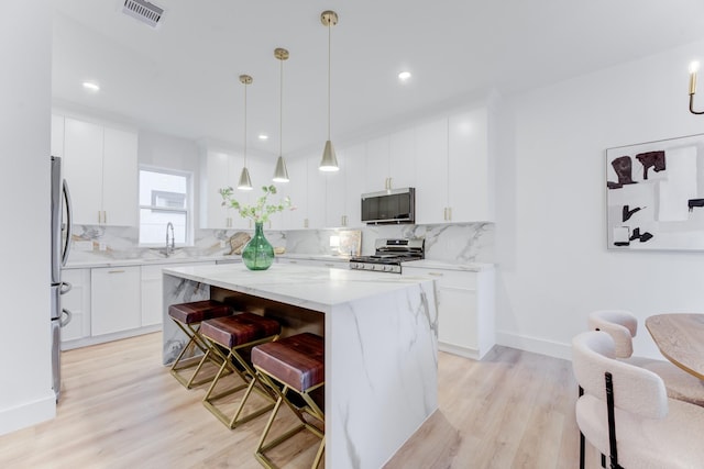 kitchen featuring range, a center island, tasteful backsplash, white cabinets, and decorative light fixtures