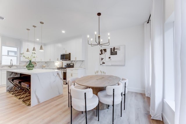 dining space featuring sink, a notable chandelier, and light wood-type flooring