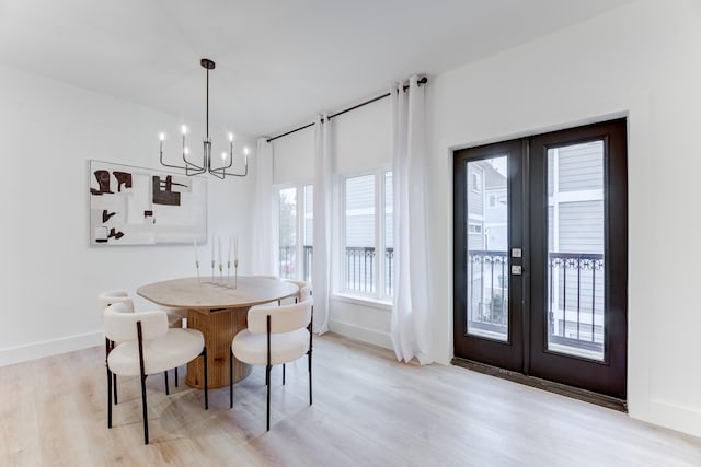 dining space with an inviting chandelier, light wood-type flooring, and french doors