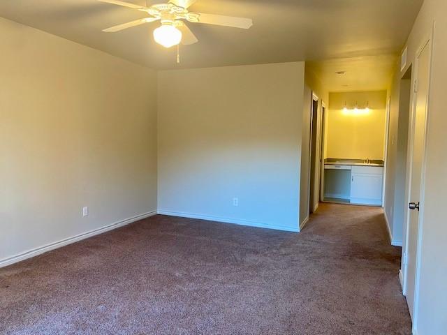 unfurnished room with dark carpet and ceiling fan