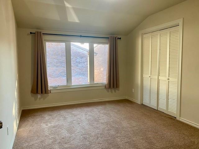 unfurnished bedroom featuring vaulted ceiling, a closet, and carpet