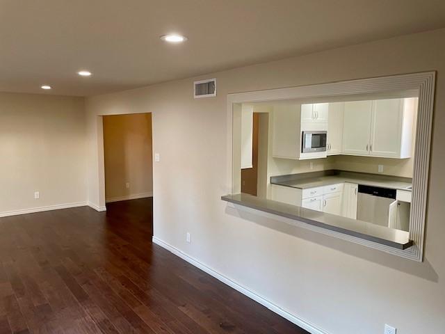 kitchen featuring white cabinetry, appliances with stainless steel finishes, and dark wood-type flooring