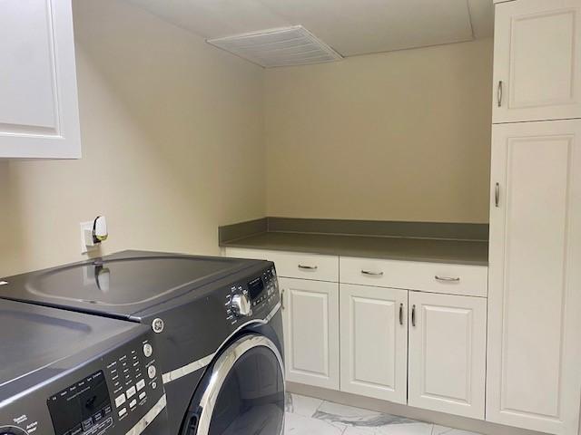 clothes washing area with cabinets and independent washer and dryer