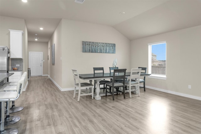 dining room with lofted ceiling and light wood-type flooring