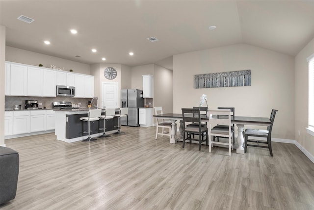 dining area with lofted ceiling and light wood-type flooring