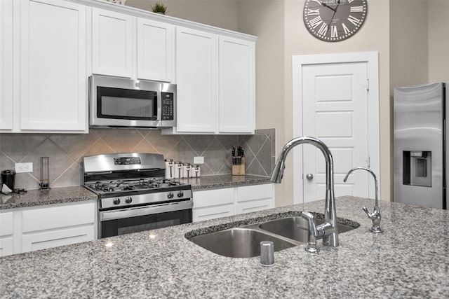 kitchen featuring light stone counters, white cabinets, appliances with stainless steel finishes, and sink