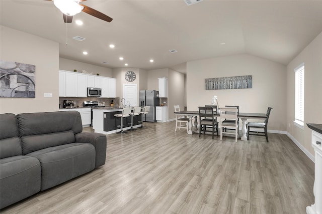 living room with lofted ceiling, sink, ceiling fan, and light wood-type flooring