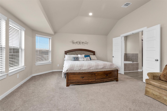 bedroom featuring connected bathroom, lofted ceiling, and carpet flooring