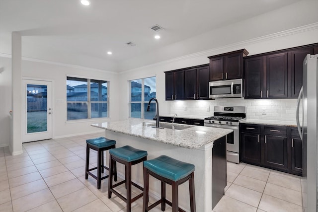 kitchen featuring light tile patterned floors, a kitchen breakfast bar, appliances with stainless steel finishes, and an island with sink