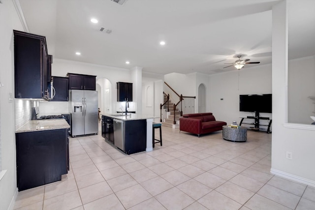 kitchen featuring light tile patterned floors, an island with sink, ceiling fan, stainless steel appliances, and sink