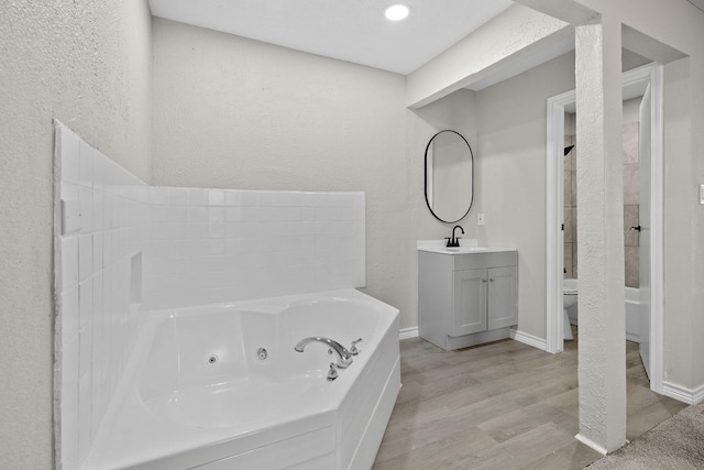 bathroom featuring toilet, vanity, hardwood / wood-style flooring, and a bath