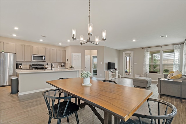 dining room with light hardwood / wood-style floors, sink, and an inviting chandelier