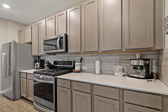 kitchen with stainless steel appliances, decorative backsplash, and gray cabinets