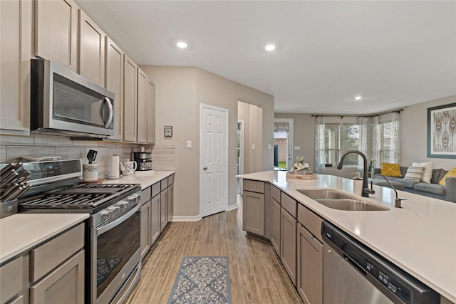 kitchen with tasteful backsplash, gray cabinets, light hardwood / wood-style floors, sink, and stainless steel appliances