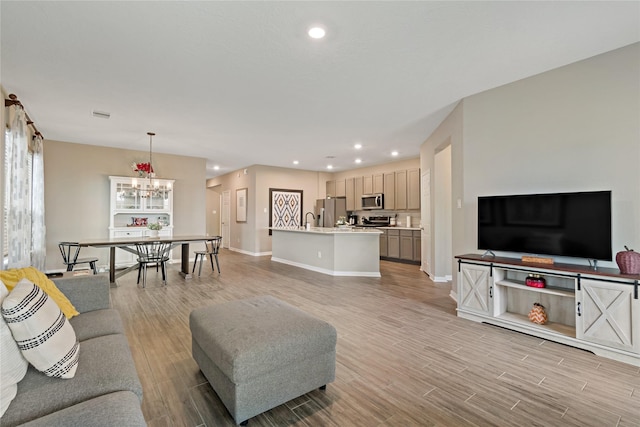 living room with sink, an inviting chandelier, and light wood-type flooring