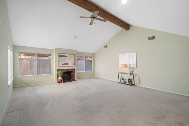 unfurnished living room with beamed ceiling, a healthy amount of sunlight, a fireplace, ceiling fan, and light colored carpet