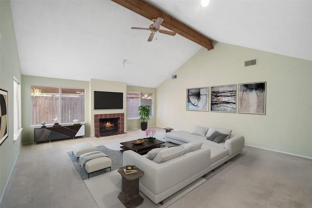 living room with a healthy amount of sunlight, light colored carpet, a tiled fireplace, and beamed ceiling